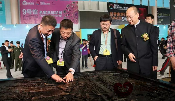 明堂红木总经理张向荣（图左二）向东阳市市长朱建军（图左一）、中国家具协会副理事长陈宝光（图右一）介绍明堂红木作品《和天下宝座沙发》