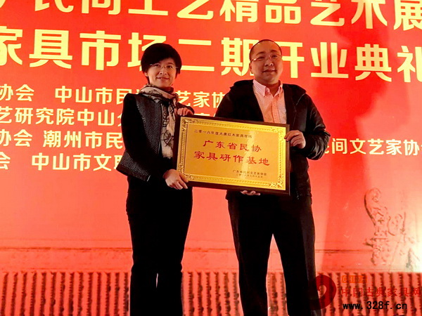广东省红木文化协会秘书长朱琪（左）为大唐红木家具市场颁发广东省民协家具研作基地牌匾，大唐红木家具市场总经理方君扬接受颁牌
