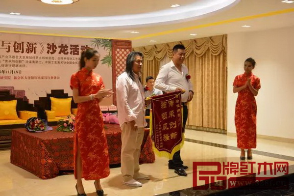 居典红木董事长尹付林向伍炳亮大师送上“传承创新，独领风骚”的锦旗