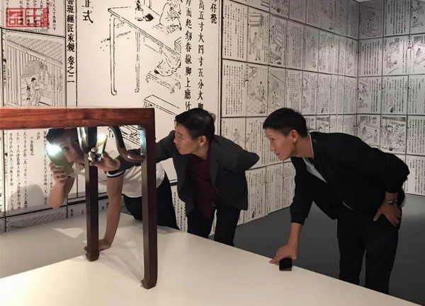 区氏臻品董事长区胜春（右二）、总经理区锦泽（右一）用手机电筒在看家具 